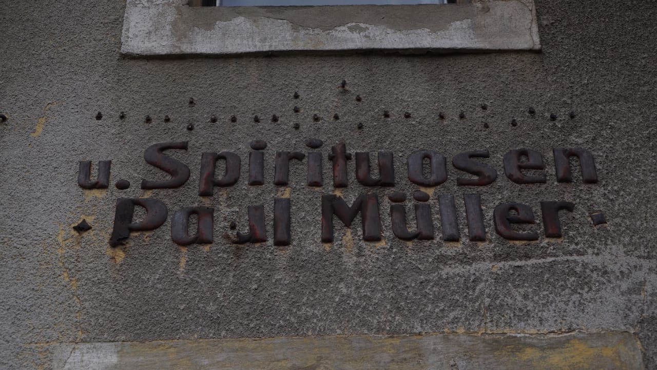 Historischer Schriftzug „u. Spirituosen Paul Müller“ in Metallbuchstaben an der Hauswand